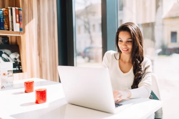 Brunettdame som bruker bærbar PC på kafe – stockfoto