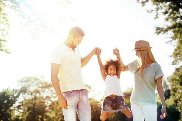 Madre y padre balanceándose hija — Foto de Stock