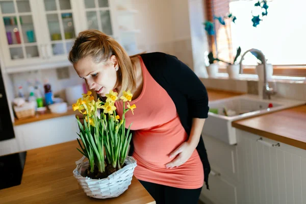Беременная женщина ухаживает за цветами — стоковое фото