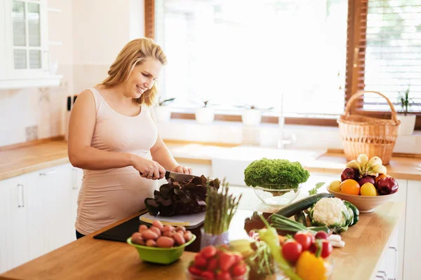 Mujer embarazada haciendo una comida en la cocina —  Fotos de Stock