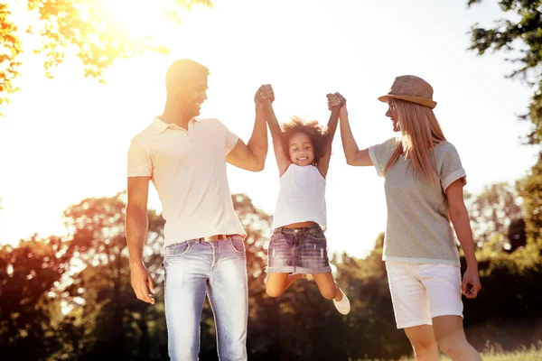 Mother and father swinging daughter Stock Image