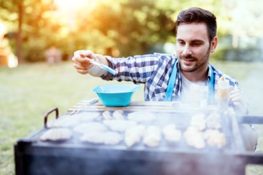 Handsome male preparing barbecue clipart