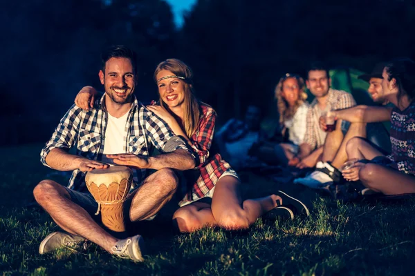 Vänner njuter musik nära lägerelden — Stockfoto