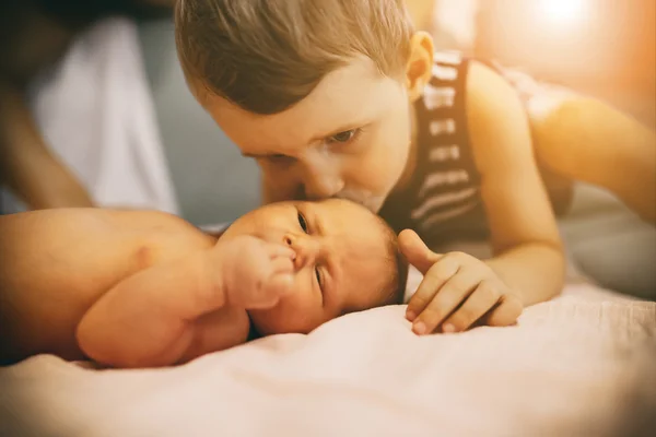 Брат целует новорожденную сестру — стоковое фото