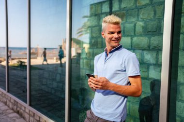 Cep telefonlu genç ve yakışıklı bir adamın açık hava portresi.