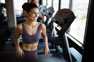 Spor salonunda egzersiz yapan çekici ve formda bir kadının görüntüsü.