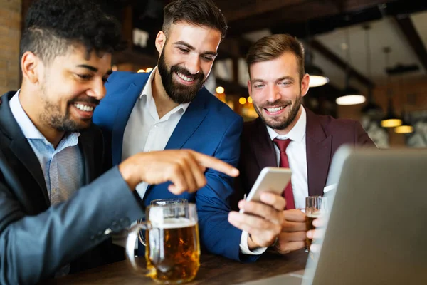 Bir grup mutlu iş adamı barda bira içip eğleniyor.