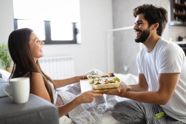 Sevgi dolu mutlu çift yatakta kahvaltı yapıyor. Sevgi dolu bir çift. Aile ilişkileri.