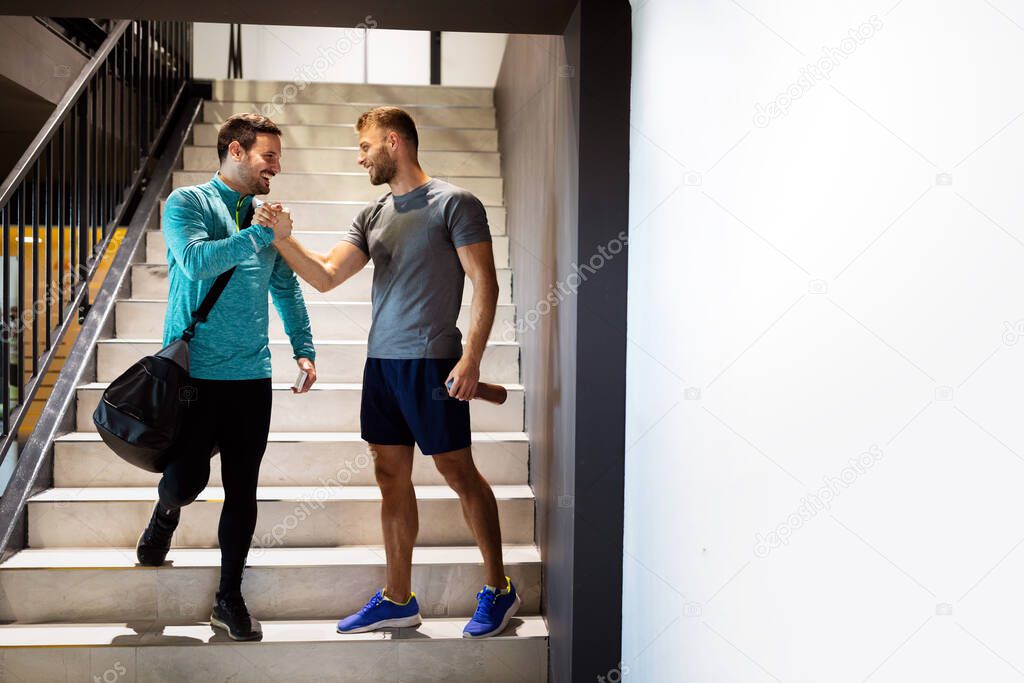 Sport, fitness, friends, lifestyle and people concept. Smiling men friends talking after workout in gym