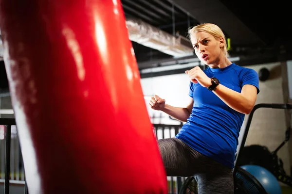 Boxing training fit woman with punching kicking bag in gym