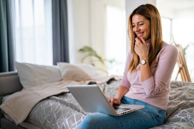 Evde dizüstü bilgisayar kullanan güzel bir genç kadın. Teknoloji konsepti