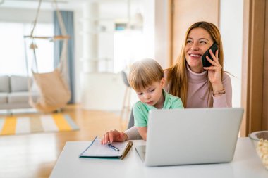 Annesi laptopunda oğluyla birlikte evde çalışıyor.
