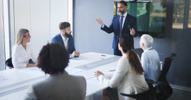 Bir grup mutlu iş adamı ofiste beyin fırtınası yapıyor.