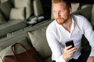 Genç işadamı cep telefonuyla mesaj gönderiyor. İş, teknoloji, insan kavramı