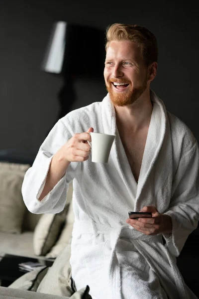 若いです幸せなハンサムな男飲む朝コーヒーでバスローブ — ストック写真