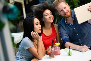 Çeşitli mutlu arkadaşlar yaz aylarında kafede eğleniyor, konuşuyor, gülümsüyor.