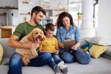 Mutlu genç aile eğleniyor, evde köpeklerle oynuyorlar.