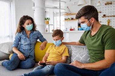 Koronavirüs salgınına karşı maske takıp evde kalan güzel bir aile.