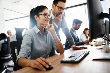 Bir grup genç iş adamı ofiste çalışıyor, beyin fırtınası yapıyor ve iletişim kuruyor.