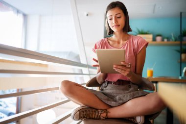 Güzel öğrenci ya da iş kadınının portresi dijital tablet kullanarak günlük kıyafetle.