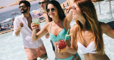 Bir grup mutlu arkadaş tropik sahilde eğleniyor, yaz tatili partisinde.