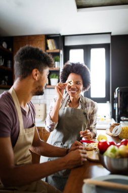 Güzel genç çift evde yemek pişirirken eğleniyor ve gülüyor.