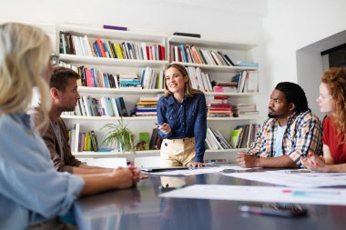 Genç mimar meslektaşları ofiste yeni bir proje üzerinde çalışırken projeleri analiz ediyorlar..