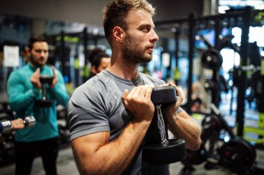 Spor salonunda egzersiz yapan yakışıklı bir genç.