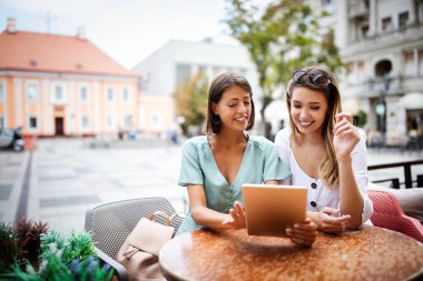 Kafede tablet kullanan ve eğlenen genç ve güzel arkadaşlar.