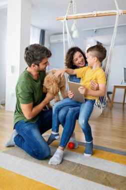 Genç ve mutlu bir aile evde vakit geçirir ve tabletteki bir şeye bakar..