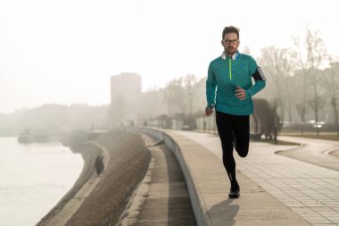 Sabah koşusundan başlayarak. Spor kıyafetleri içinde yakışıklı bir delikanlı parkta koşuyor.