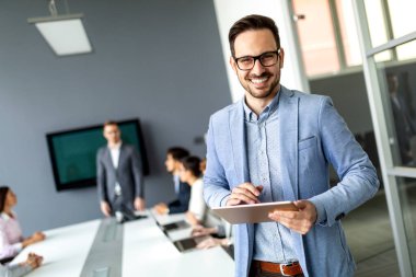 İş adamları yönetim kurulu toplantısı yapıyor, modern ofiste çalışıyorlar.
