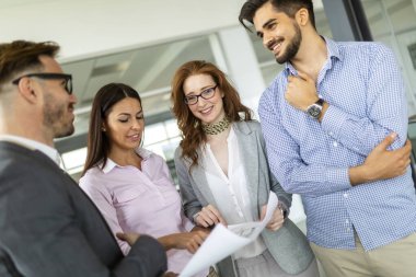 Mutlu iş ortakları ofiste belgeleri ve fikirleri tartışıyor.