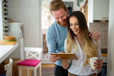 Mutlu romantik çift tablet kullanıyor ve evde kahve içiyor.