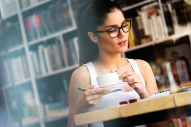 Çalışan ya da ders çalışan güzel, gülümseyen bir kadının portresi.