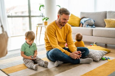 Mutlu baba ve oğul evde cep telefonuyla oyun oynuyor. Teknoloji bağımlılığı aile sorunu kavramı