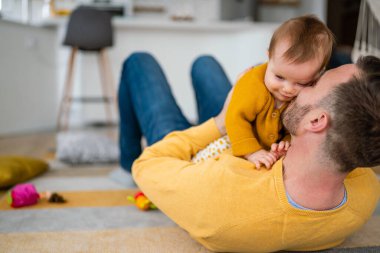 Sevecen baba ve küçük kızı evde oynaşıp kaynaşıyorlar.
