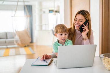 Annesi laptopunda oğluyla birlikte evde çalışıyor.