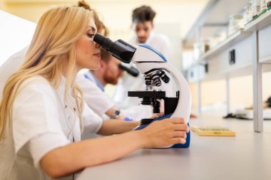 Laboratuvarda çalışan bir grup genç öğrenci ve bilim adamları.