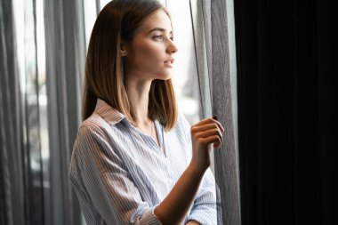 Pencerenin önünde duran güzel bir kadının portresi.