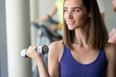 Spor salonunda halterle egzersiz yapan güzel bir kadın.