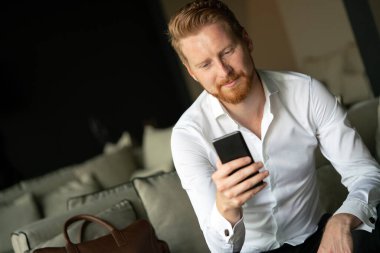 Akıllı telefon kullanan başarılı genç bir iş adamı.