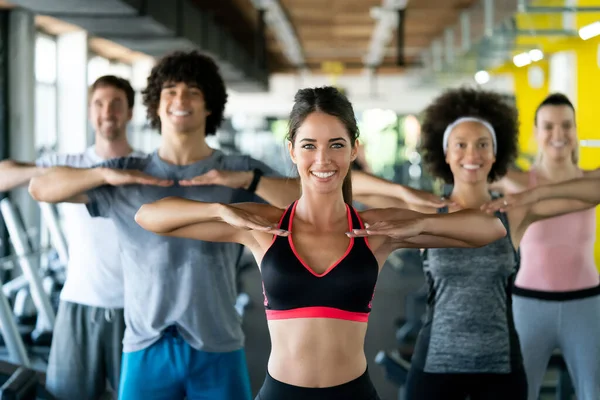 Group of fit young people at the gym exercising