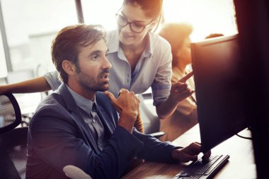 Bir grup genç iş adamı ofiste çalışıyor, beyin fırtınası yapıyor ve iletişim kuruyor.