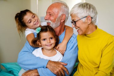 Mutlu büyükanne ve büyükbabalar evde torunlarıyla eğleniyor.