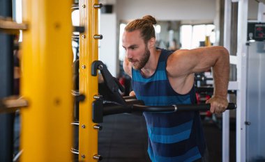 Spor salonunda makine üzerinde egzersiz yapan yakışıklı bir adam.