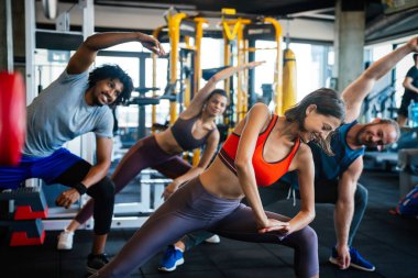 Spor salonunda egzersiz yapan mutlu bir grup genç.