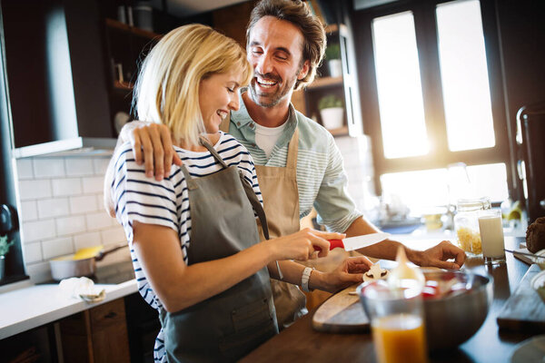 Portrait of happy couple cooking together in the kitchen at home