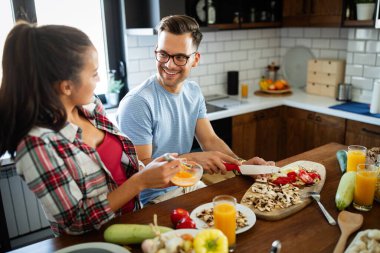 Güzel genç bir çift mutfakta birlikte yemek pişirirken eğleniyor.