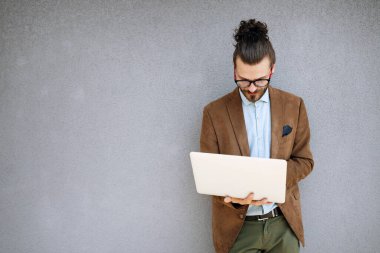 Dışarıda dizüstü bilgisayar kullanan genç bir iş adamının portresi.